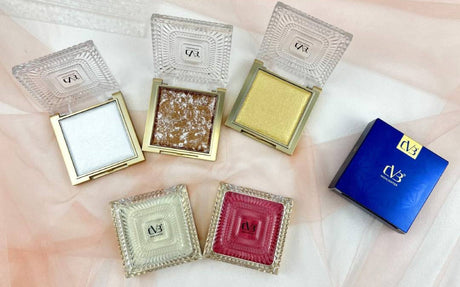 Collection of square compact mirrors with different colored contents on a light pink background.