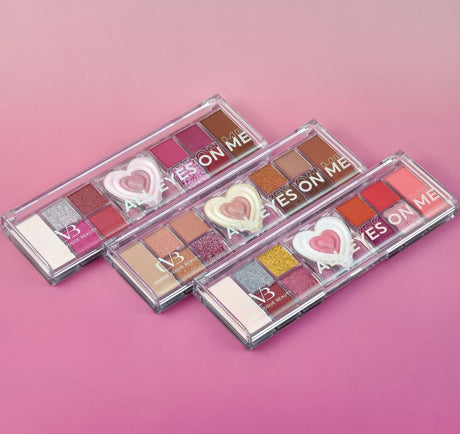 Three makeup palettes with heart-shaped designs on a pink background