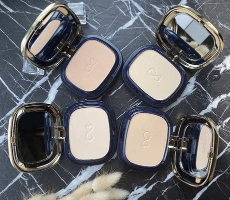 Makeup compacts with visible brand logo on a marble surface