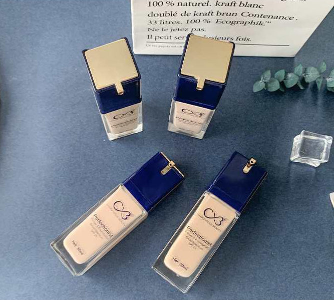 Four cosmetic bottles with blue and gold accents on a blue surface.