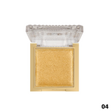 Gold-colored makeup compact with clear lid on a white background