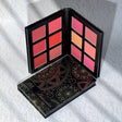 Makeup palette with colorful shades on a white textured surface