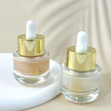 Two glass dropper bottles with gold caps on a beige background