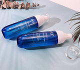 Two blue skincare bottles with white caps on a light gray surface.