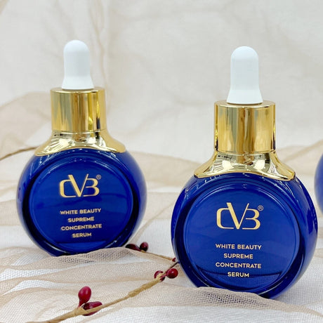 Three blue skincare bottles with gold caps on a textured surface.