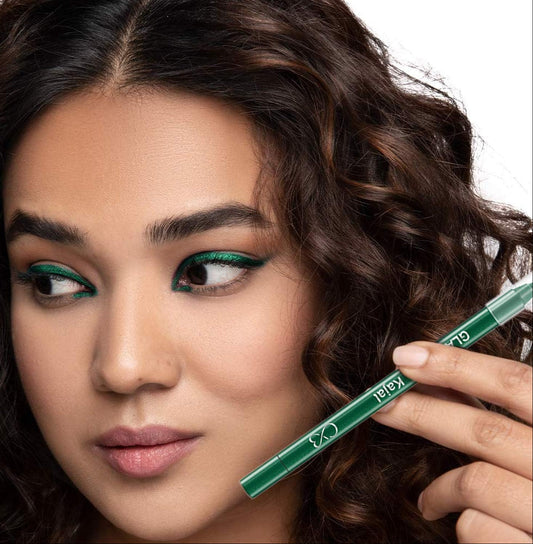 Woman with green eye makeup holding a green eyeliner pencil.