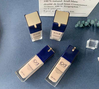 Four cosmetic bottles with blue and gold accents on a blue surface.